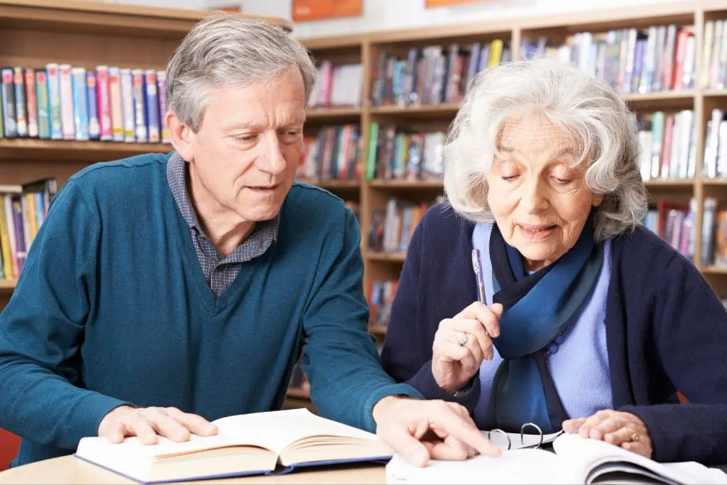 a older man and woman looking at a book