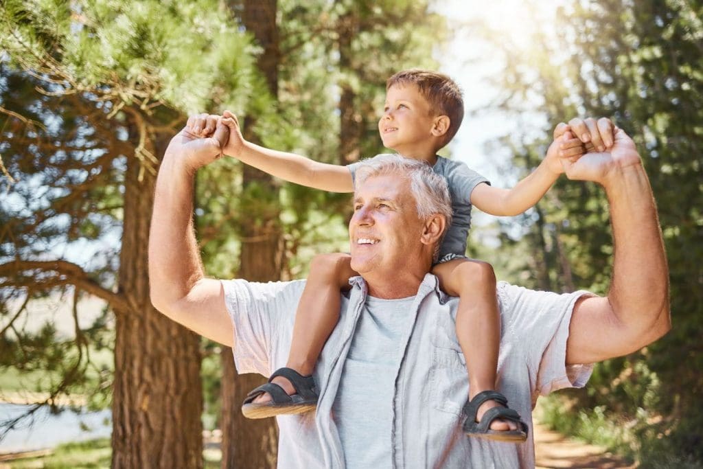 Senior man walking with his grandson on his shoulders